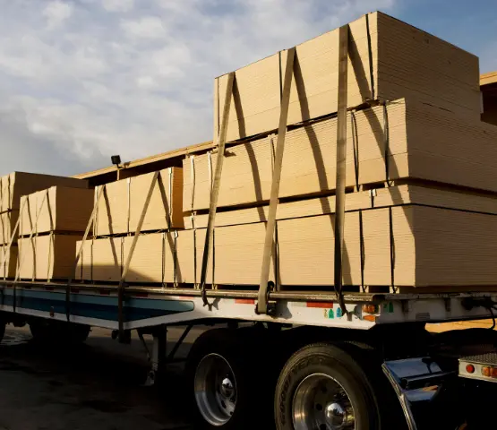 Flatbed trailer loaded with strapped stacks of building panels